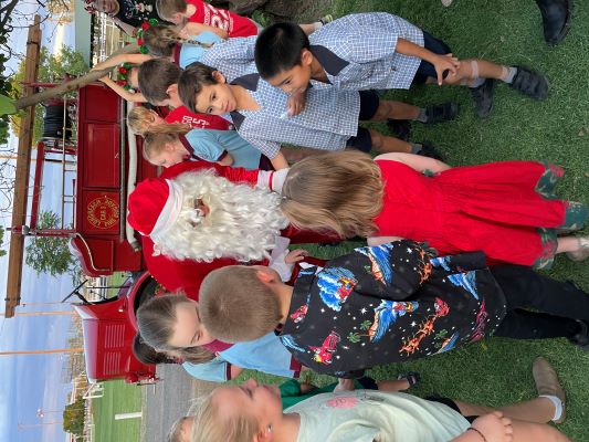 a man dressed as santa surrounded by lots of young kids